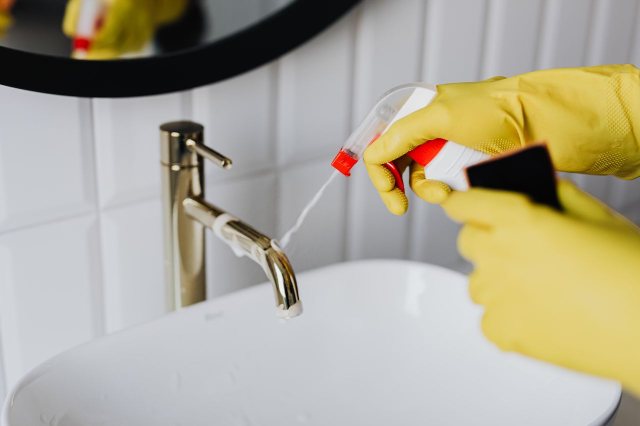 why-choose-us From above anonymous housekeeper in yellow rubber gloves spraying cleaner to chrome water faucet in bathroom